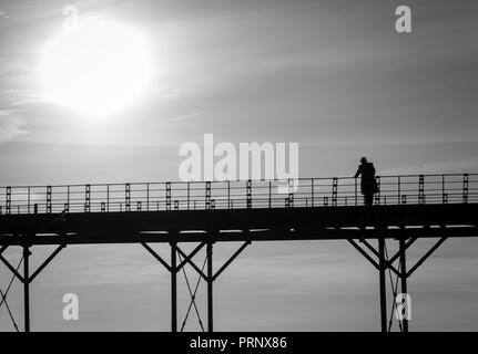 Monochrome einzelner Mann denken auf einem alten englischen Victorian seaside Pier Stockfoto