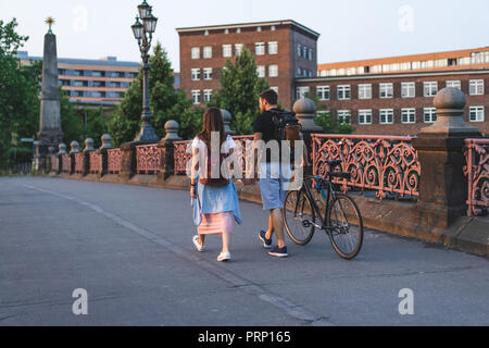 Ansicht der Rückseite des Paares mit Rucksäcken und Fahrrad auf Brücke in Berlin, Deutschland Stockfoto