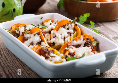 Gefüllte Paprika mit Hackfleisch und Mozzarella in Keramik Teller auf rustikalen Holztisch Stockfoto