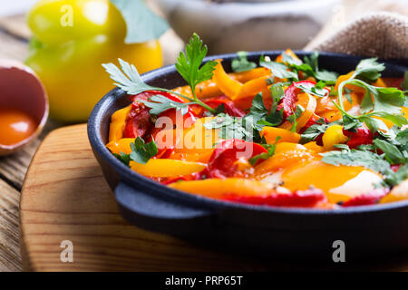 Shakshuka, Spiegelei, Tomaten und Paprika Sauce aus Gusseisen Skillet auf rustikalen Holztisch gekocht Stockfoto