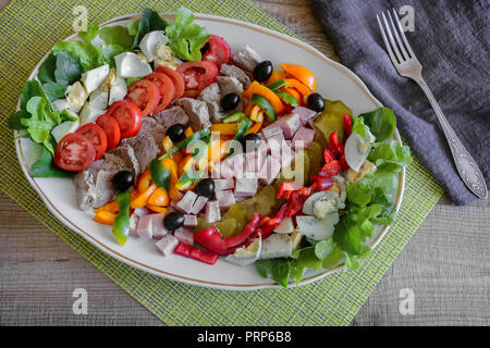 Ein beliebtes Gericht der amerikanischen Küche - Cobb Salat, bestehend aus grünen, Eier, Tomaten, Käse, Fleischwaren, in Reihen gestapelt auf eine große Schüssel und poure Stockfoto