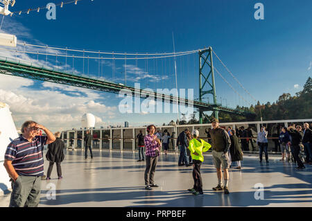 Kreuzfahrtschiff Passagiere auf der Oberseite des Holland America Die Volendam, wie es unter der Lions Gate Bridge in Burrard Inlet, Vancouver, British Columbia, Kanada auf dem Weg nach Alaska, USA. Stockfoto