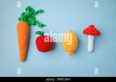 Set aus Gewirken Spielzeug Zitrone, Karotte, Apfel, amanita auf blauem Hintergrund. Früher taktile Entwicklung der Kinder, Handwerk Spielzeug, vegetarisches Menü Konzept Stockfoto