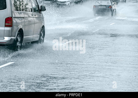 Stadt Straße überflutet nach starkem Regen. Autos durch große Wasser Pfützen fahren in der Geschwindigkeit Stockfoto