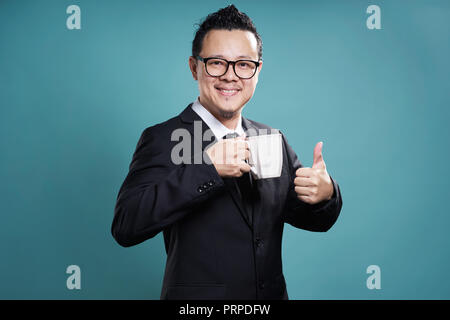 Geschäftsmann in Anzug lächeln und genießen Sie Kaffee mit Daumen oben-Geste. Stockfoto