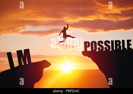 Mann springen über unmöglich oder über Cliff am sunset Hintergrund Stockfoto