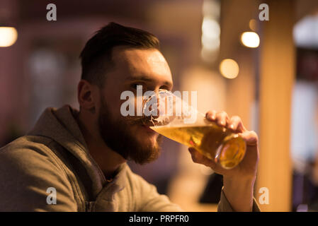Ein hübscher junger hipster Mann trinkt ein Bier an der Bar. Stockfoto