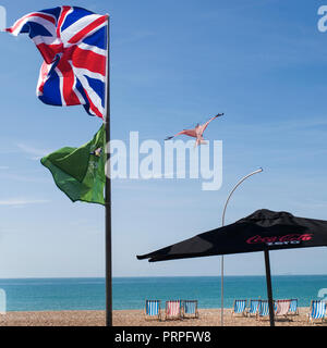 Union Flagge im Wind über Brighton Beach und Liegestühlen Stockfoto
