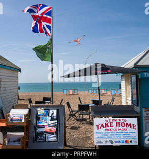 Union Flagge im Wind über Brighton Beach und Liegestühlen Stockfoto