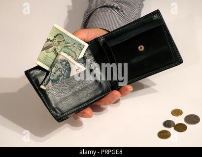 Schwarzen Mappe in männlicher Hand mit einigen Papiergeld und Münzen. Geld sparen Konzept Stockfoto