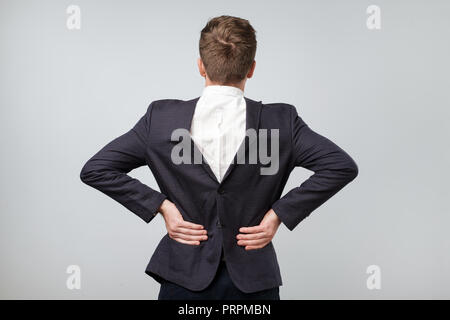 Studio shot eines reifen kaukasischen Mann mit seiner Klage auf Rückwärts, grauer Hintergrund Stockfoto