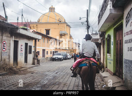 Lokaler Mann reitet Maultier nach unten eine typische Straße in Santa María de Jesús, eine kleine Stadt Antigua in Guatemala Stockfoto