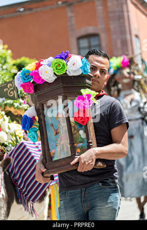 Eine mexikanische Mann trägt eine Statue des Heiligen Michael während der jährlichen Parade feiern die Städte Schutzpatron am Fest des Hl. Michael 30. September in San Miguel de Allende, Mexiko 2018. Das Festival ist eine 4-tägige Veranstaltung mit Prozessionen, Umzügen und bis spät in die Nacht Feuerwerk Schlacht. Stockfoto