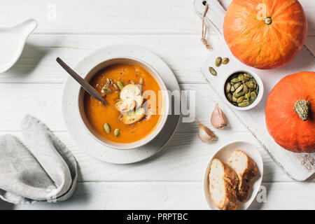 Ansicht von Kürbis Cremesuppe mit Samen und Zwieback in der Schüssel auf dem Tisch Stockfoto