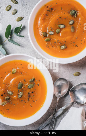 Blick von oben auf die Platten mit Kürbis creme Suppe mit Samen auf Tisch Stockfoto