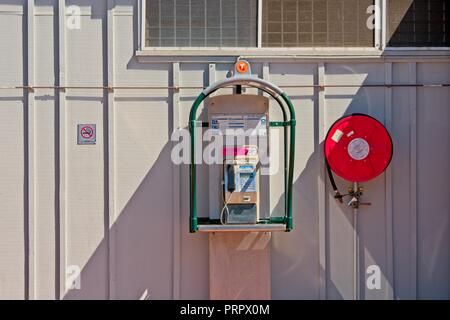 Öffentliches Telefon hängen an Hauswand Stockfoto