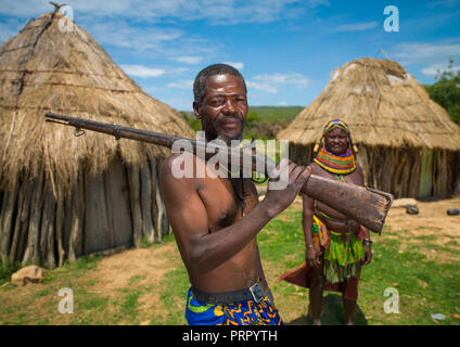 Mumuhuila Stamm Mann mit einem Gewehr in seinem Dorf, Huila Provinz, Chibia, Angola Stockfoto