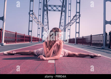 Angenehme junge Frau tun Splits auf der Brücke Stockfoto