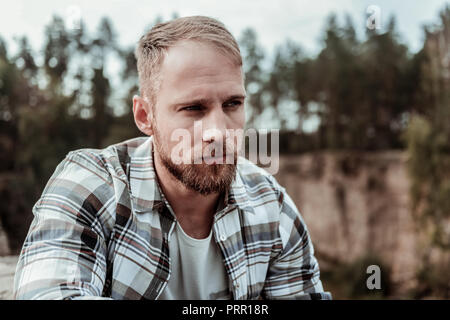 Gut aussehende dunkle Augen, Mann, Quadrat Shirt draussen frische Luft genießen. Stockfoto