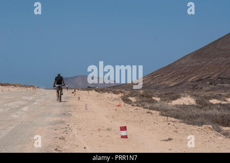 Lanzarote, Kanarische Inseln: junge Radfahren auf dem Schmutz der Straße zum Strand Playa de Las Conchas im Norden von La Graciosa, die Inselgruppe Chinijo Inseln Stockfoto