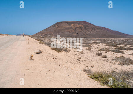 Lanzarote, Kanarische Inseln: junge Radfahren auf dem Schmutz der Straße zum Strand Playa de Las Conchas im Norden von La Graciosa, die Inselgruppe Chinijo Inseln Stockfoto