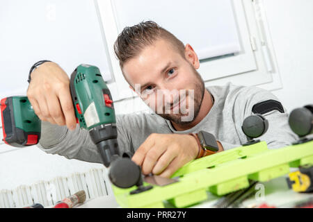 Ein junger Mann DIY mit elektrischen Bohrmaschine Stockfoto