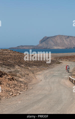 Lanzarote, Kanarische Inseln, Spanien: die Menschen gehen auf die Straße vom Strand Playa de Las Conchas im Norden der Insel La Graciosa Stockfoto