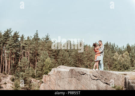 Lieben starke Freund umarmte seinen süßen Freundin stehen am Rand der Felsen Stockfoto