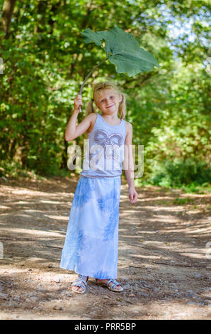 Schöne kaukasische Mädchen mit grünem Klette Anlage im grünen Wald Stockfoto