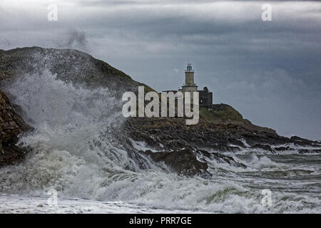 Wellen gegen die Felsen durch Mumbles Leuchtturm in Armband Bay, Swansea, Wales, Großbritannien Stockfoto