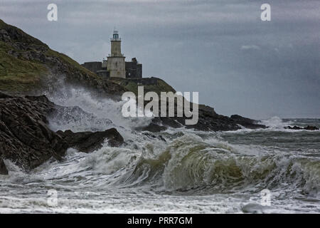 Wellen gegen die Felsen durch Mumbles Leuchtturm in Armband Bay, Swansea, Wales, Großbritannien Stockfoto