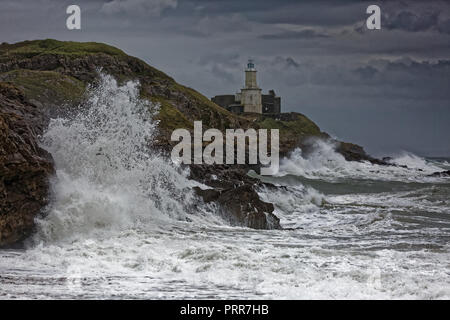 Wellen gegen die Felsen durch Mumbles Leuchtturm in Armband Bay, Swansea, Wales, Großbritannien Stockfoto