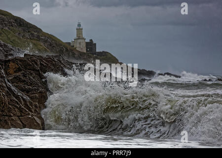 Wellen gegen die Felsen durch Mumbles Leuchtturm in Armband Bay, Swansea, Wales, Großbritannien Stockfoto