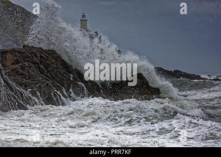 Wellen gegen die Felsen durch Mumbles Leuchtturm in Armband Bay, Swansea, Wales, Großbritannien Stockfoto