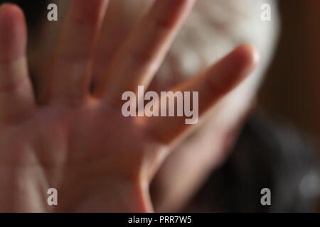 Ein Mann versteckt sein Gesicht mit ausgestreckter Hand und Faust. Stockfoto