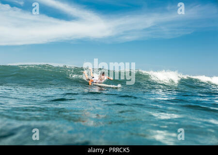 Fernsicht auf männliche Sportler schwimmen auf Surfen im Meer am Sandstrand von Nusa Dua, Bali, Indonesien Stockfoto