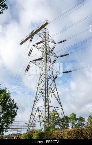 Ein Strom Pylon mit einem großen temporären Wiege Plattform bereit für Arbeitnehmer zu verwenden, wenn Sie das Hochspannungskabel Kabel ändern Stockfoto