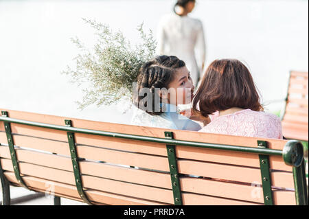 Hanoi, Vietnam - 16. Oktober 2016. Junge Frauen mit einem Blumenstrauß entspannend am Ufer der Schwert See bei Sonnenuntergang. Stockfoto