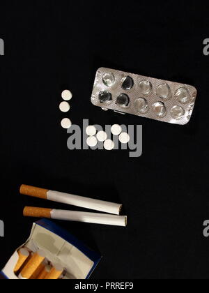 Weiße Tabletten (Pillen) mit dem Blister und eine Packung Zigaretten Stockfoto