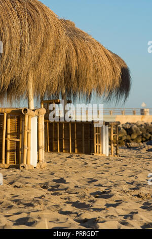 Stroh Sonnenschirme in goldenem Licht bei Sonnenuntergang auf einem schönen Nachmittag im September auf Mallorca, Spanien. Stockfoto