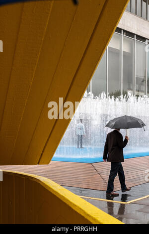 England, London, South Bank - Mann mit Regenschirm in der Royal Festival Hall Stockfoto