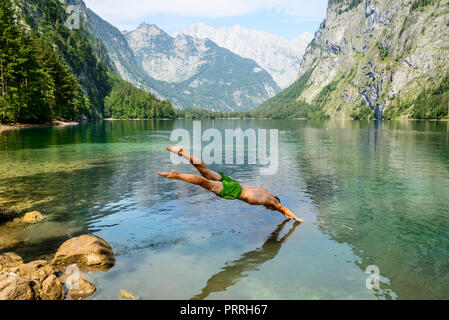 Junger Mann springt in am Obersee, Schwimmen, See, Berg Landschaft, in der Rückseite Watzmann massif, Salet am Königssee Stockfoto