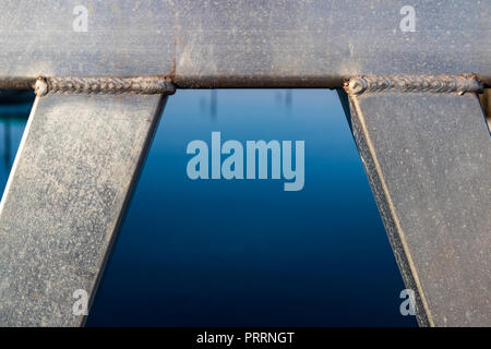 Geschweißte Rohre aus Aluminium Strahl in einem Bogen mit Wasser in die Mitte gerahmt Stockfoto