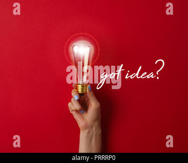 Frau mit Vintage Glühlampe auf rote Oberfläche mit' Idee?' Schriftzug Stockfoto