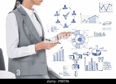 Zugeschnittenes Bild der Unternehmerin lehnte sich auf Tabelle und halten Unterlagen isoliert auf Weiss mit Hand gezeichnete Geschäft Diagramme Stockfoto