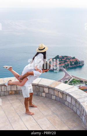 Freund huckepack mit Freundin am Aussichtspunkt in der Nähe der Insel Sveti Stefan in Budva, Montenegro Stockfoto