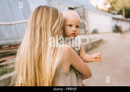 Teilweise mit Blick auf die Mutter Holding Baby in Leinen Kleidung auf Händen an Land Stockfoto