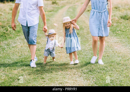 Familie mit zwei Kindern halten sich an den Händen und laufen auf Sommer feild Stockfoto