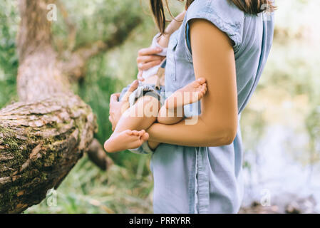 7/8-Ansicht von Mutter Holding Baby auf Händen Stockfoto