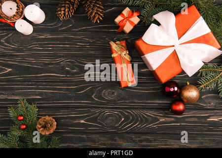 Blick von oben auf die geschenkboxen, Weihnachtskugeln und Tannen Zweigen auf Holz- Oberfläche Stockfoto